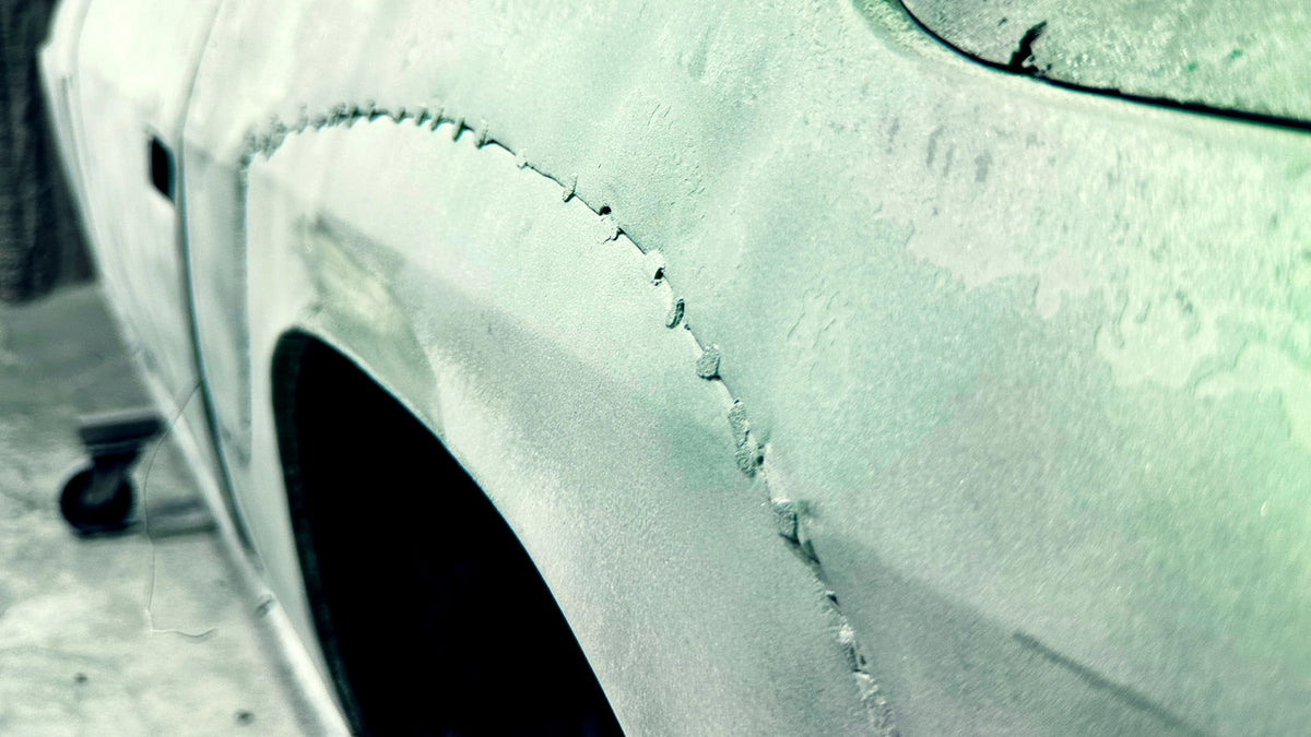 Detailaufnahme einer entlackten Fahrzeugkarosserie nach der Bearbeitung durch die Firma ecoBlast in Nettetal. Die Nahaufnahme zeigt das freigelegte Metall und die Schweißnähte am Radlauf eines Oldtimers, die nach der professionellen Oberflächenreinigung präzise sichtbar werden.