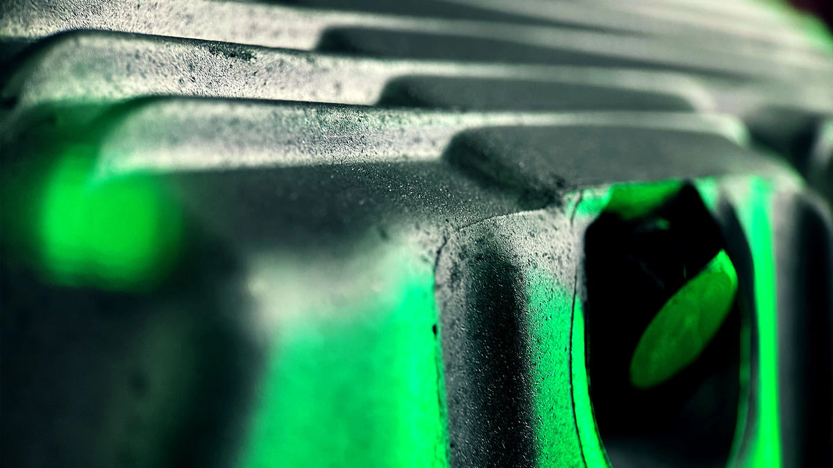 Makroaufnahme einer metallischen Oberfläche mit markanten grünen Lichtreflexionen nach der Bearbeitung durch die Firma ecoBlast in Nettetal. Das Bild verdeutlicht die feine Textur und Reinheit des Materials, die durch professionelle Strahltechnik erzielt wurde.