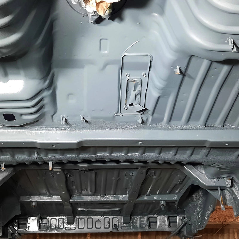 Ansicht eines komplett entlackten und gereinigten Fahrzeugunterbodens durch die Firma ecoBlast in Nettetal. Die Aufnahme zeigt die präzise gesäuberten Bodenbleche und Profile in einem gleichmäßig grauen Metallfinish, das eine optimale Grundlage für den neuen Korrosionsschutz bietet.