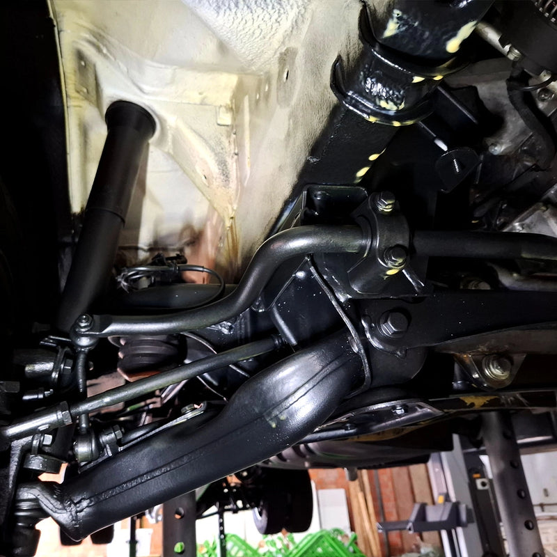 Detailansicht einer professionell versiegelten Radaufhängung durch die Firma ecoBlast in Nettetal. Das Bild zeigt Querlenker, Stabilisator und weitere Fahrwerkskomponenten in einem hochwertigen, schwarzen Schutzfinish nach der gründlichen Reinigung und Korrosionsschutz-Behandlung.