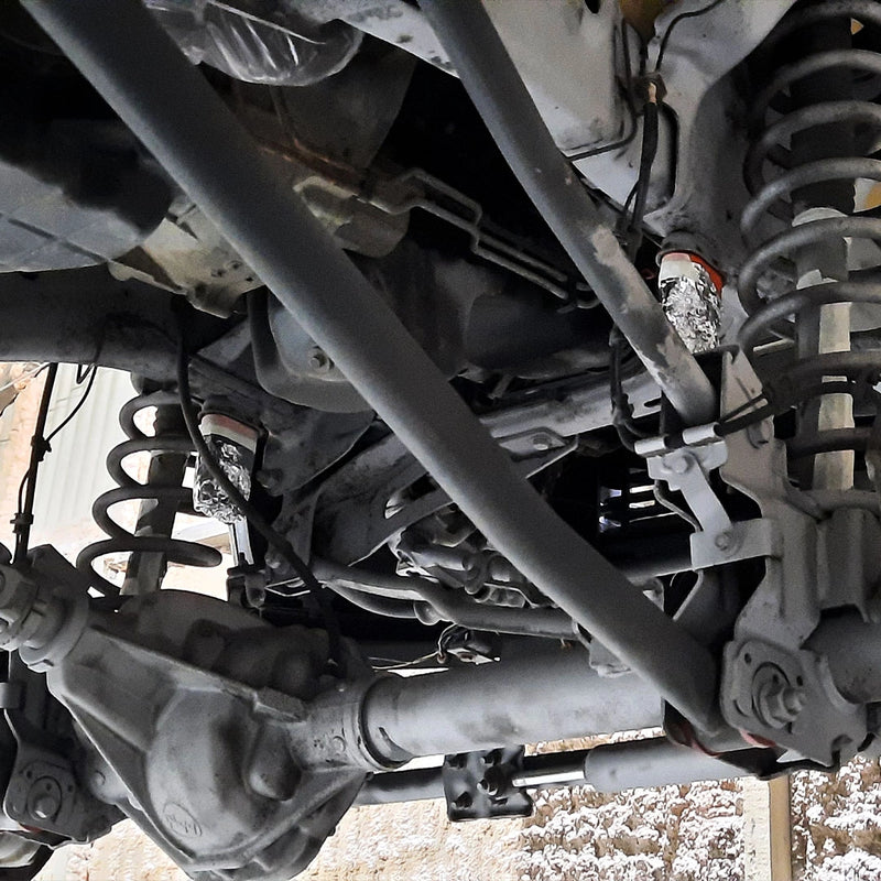 Detailansicht eines professionell gereinigten Fahrzeugunterbodens bei der Firma ecoBlast in Nettetal. Die Aufnahme zeigt Achskomponenten, Federn und das Differentialgehäuse im sauberen Metallzustand nach der Strahlbehandlung, wobei sensible Anschlüsse und Bauteile zum Schutz sorgfältig maskiert wurden.