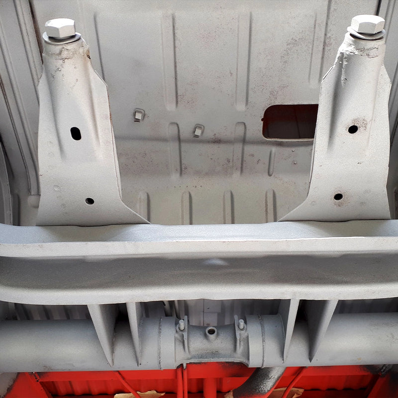 Detailansicht eines professionell entlackten und entrosteten Fahrgestells durch die Firma ecoBlast in Nettetal. Das Bild verdeutlicht das saubere, matte Metallfinish der Träger und des Unterbodens nach der Bearbeitung mit Strahltechnik, was die ideale Basis für eine fachgerechte Restauration darstellt.